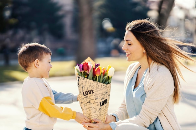 Um filho dando flores para sua mãe no dia das mães enquanto passava o dia em um parque