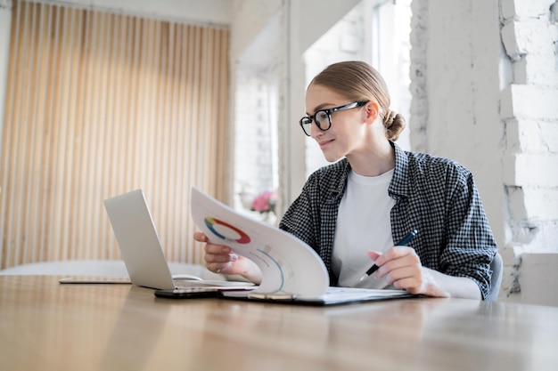 Um financista em um terno formal uma mulher com óculos trabalhando com documentos usa um laptop