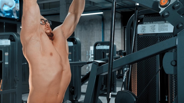 Um fisiculturista de homem atraente fazendo exercícios de força no ginásio de esportes