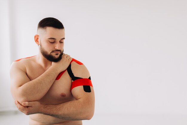 Foto um fisioterapeuta profissional que grava fita elástica de cinesiologia nos pacientes do braço e ombro.