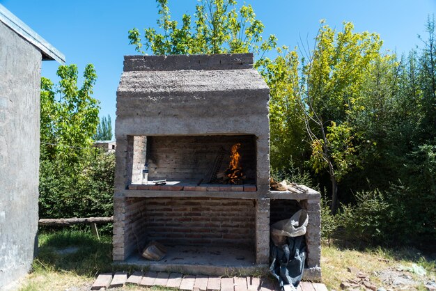 Um forno de tijolos com fogo no meio fica na sombra.