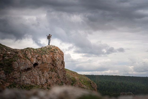 Um fotógrafo de viagens viajante no topo de uma montanha fotografa a paisagem natural Fotografia de paisagem contra o espaço da cópia do céu