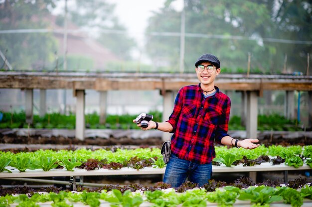 Um fotógrafo do sexo masculino está tirando fotos em seu jardim de saladas e curtindo a fotografia.