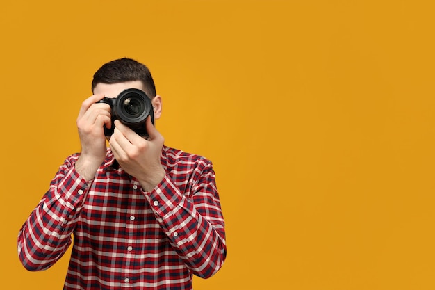 Um fotógrafo masculino no processo de tirar fotos em um fundo amarelo