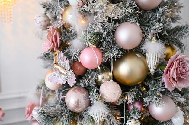 Um fragmento de uma árvore de natal decorada em tons suaves de rosa