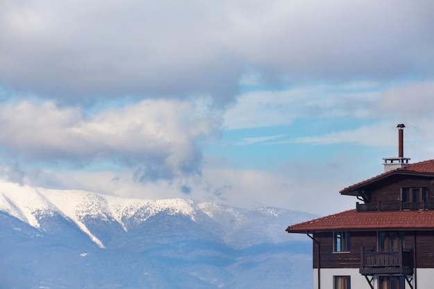 Um fragmento de uma casa de estilo europeu no fundo dos picos das montanhas cobertas de neve