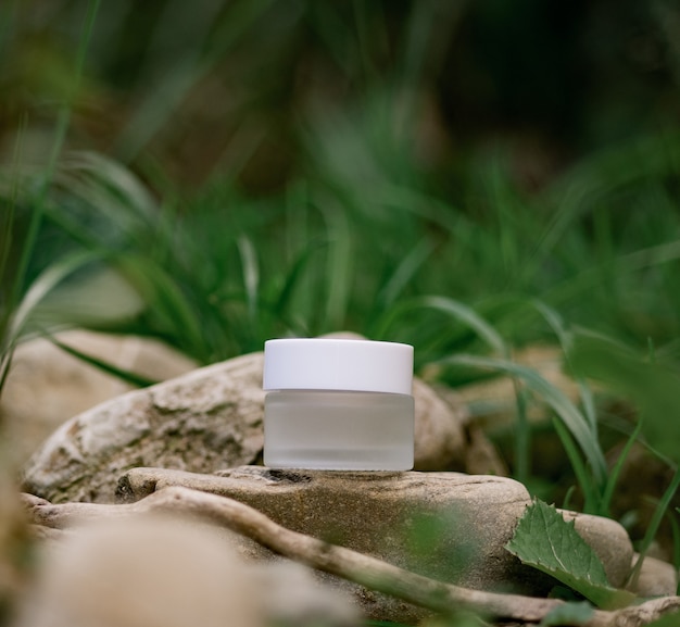 Um frasco de cosmético fica em cima de uma pedra. Composição natural