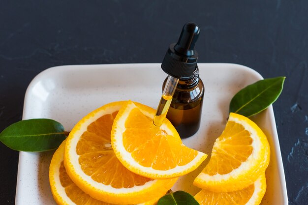 Um frasco de cosmético ou óleo essencial da medicina alternativa à laranja. ângulo próximo. fundo preto.