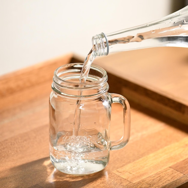 Um frasco de vidro com uma garrafa de água sendo despejada nele.