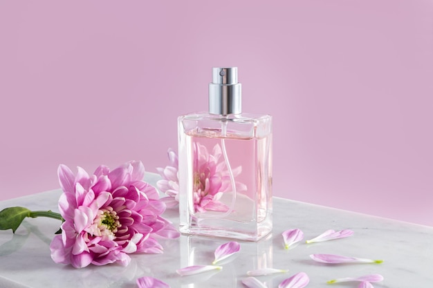 Um frasco elegante de perfume ou spray feminino fica em parte de um pódio de mármore branco e uma frente de fundo rosa vê o conceito de beleza