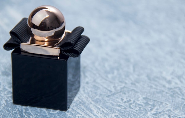 Um frasco preto de perfume feminino. Perfume feminino estiloso em um fundo cinza