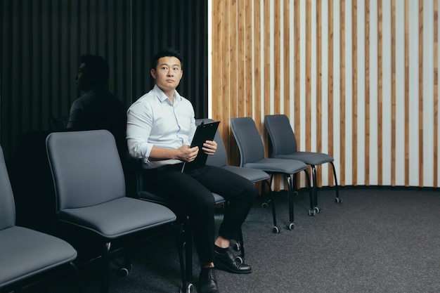 Um funcionário asiático está esperando no saguão um homem está conseguindo um emprego em um escritório moderno