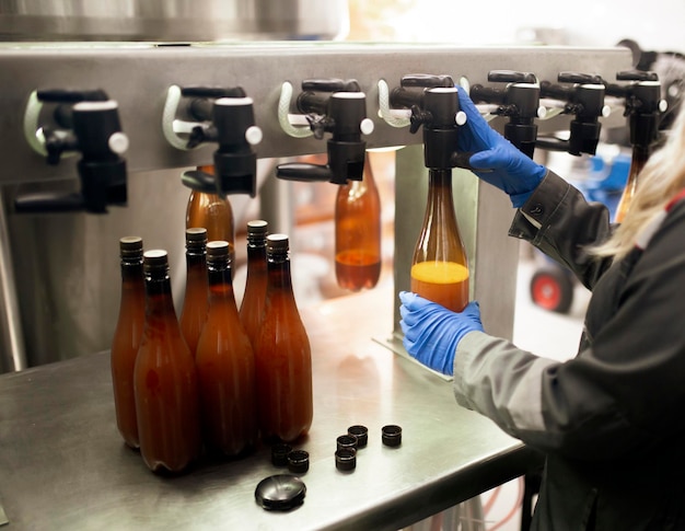 Foto um funcionário da fábrica enchendo uma nova garrafa de plástico com cerveja da torneira