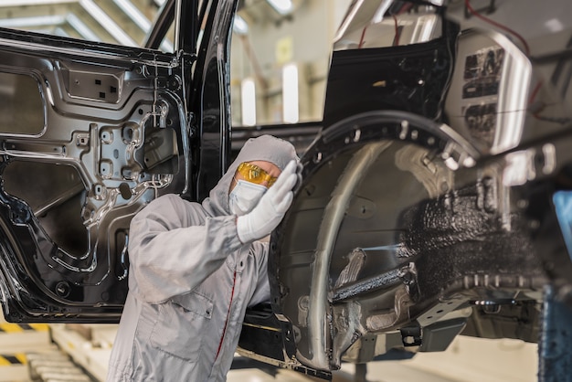 um funcionário da oficina de pintura de uma fábrica de automóveis verifica a qualidade da superfície pintada