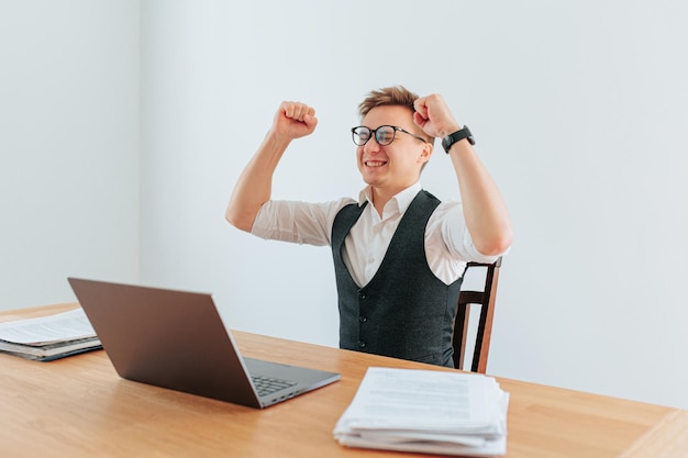 Um funcionário de escritório está sozinho em seu cubículo mãos triunfalmente levantadas no ar enquanto celebra um recente sucesso o olhar de satisfação e felicidade em seu rosto é inegável