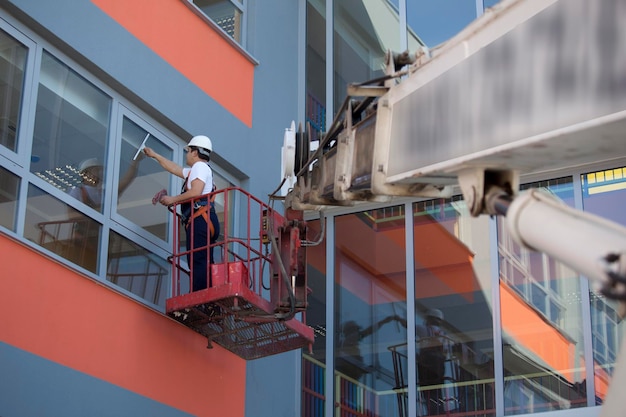 Um funcionário de um serviço de limpeza profissional de macacão lava o vidro das janelas da fachada do edifício Limpeza de vitrine para lojas e empresas