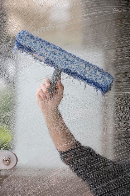 Um funcionário de um serviço de limpeza profissional de macacão lava o vidro das janelas da fachada do edifício limpeza de vitrine para lojas e empresas