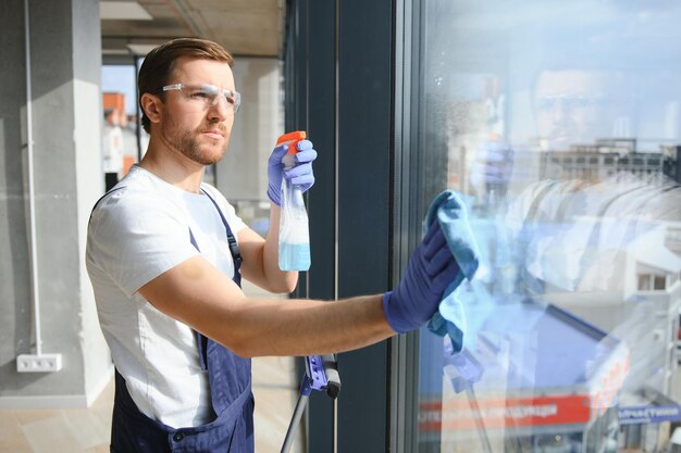 Um funcionário de um serviço de limpeza profissional lava o vidro das janelas do prédio Limpeza de vitrines para lojas e empresas