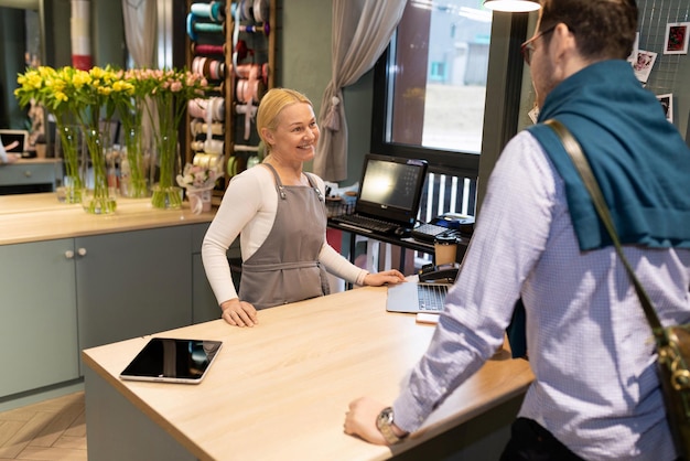 Um funcionário de uma floricultura atende gentilmente um cliente no balcão de trabalho