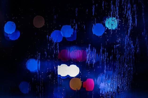 Um fundo abstrato de luzes policiais vermelhas e azuis bokeh através de vidro molhado à noite fechada