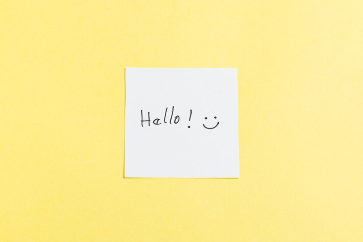Foto um fundo amarelo com um papel branco que diz olá com um rosto sorridente