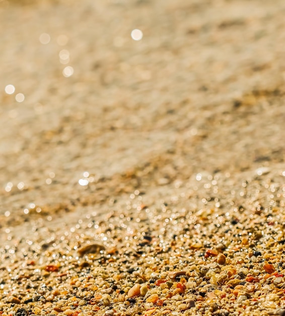 Um fundo de areia pequenas pedras e ondas fluindo na praia conceito de férias de verão