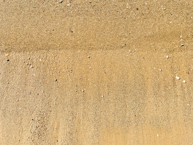 Um fundo de pequenos seixos de areia e onda fluida na praia do mar conceito de férias de verão