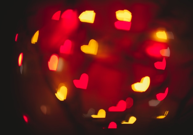 Um fundo desfocado com bokeh em forma de coração em cores diferentes. Fundo desfocado