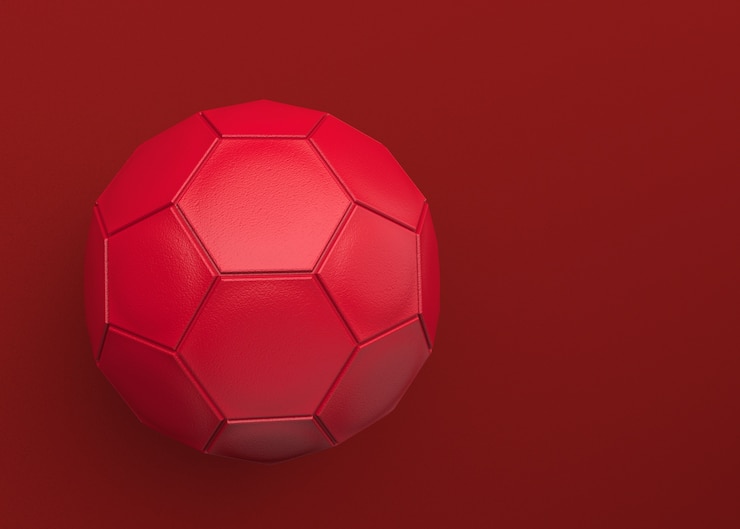 Foto um futebol de couro vermelho no fundo da obscuridade do espaço da cópia.
