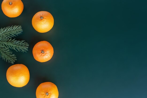 Um galho de uma árvore de Natal sem brinquedos e tangerinas em um fundo verde. Cartão postal de ano novo.