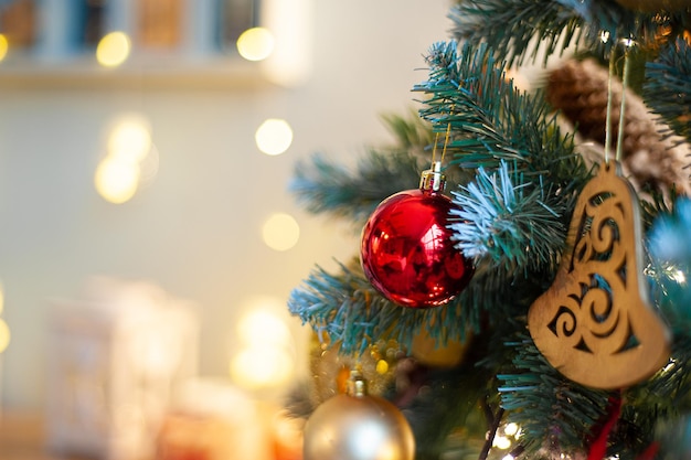 Um galho de uma árvore de Natal verde decorada com um foco suave no interior. Um lugar para texto. madeira e decoração festiva vermelha da casa.