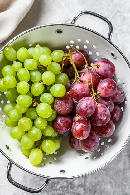 Um galho de uvas verdes e vermelhas em uma peneira