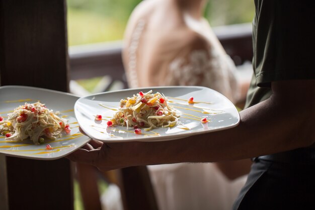 Foto um garçom com um prato de salada. milionário maurício.