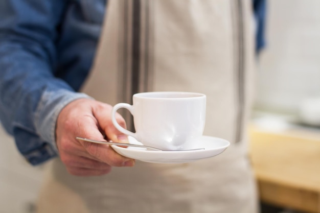 Foto um garçom com uma xícara de café na mão em um bar