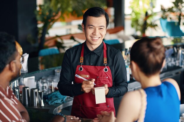 Um garçom de restaurante a falar com um casal.