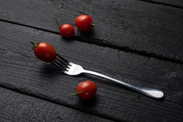 Um garfo com um tomate sobre uma mesa preta