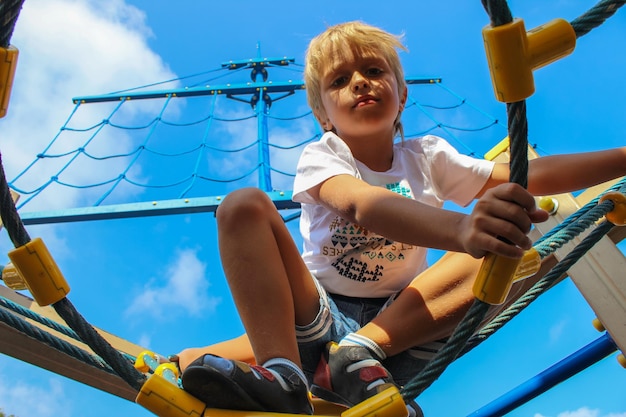 Um garotinho brinca em passeios brilhantes e coloridos no playground no verão