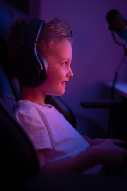 Foto um garotinho com fones de ouvido e um microfone joga jogos de computador transmite jogos de console