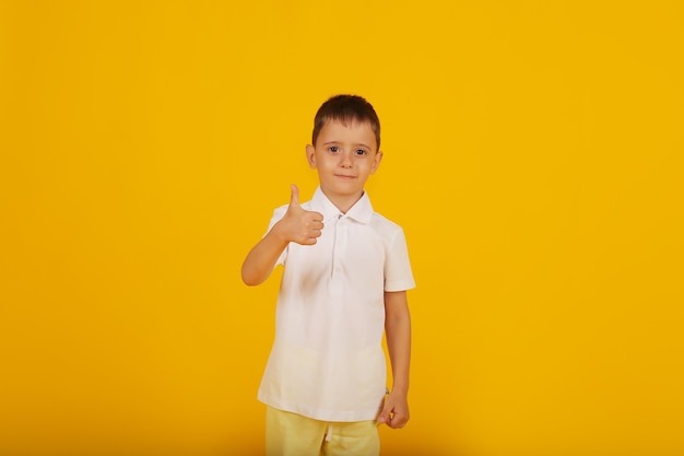 um garotinho com uma camiseta branca e calças amarelas sobre um fundo amarelo é uma emoção