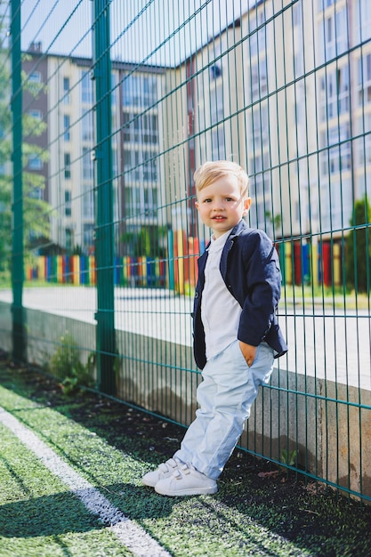 Um garotinho de 2 anos de camisa e jaqueta fica na rua Traje clássico infantil para o feriado Moda infantil