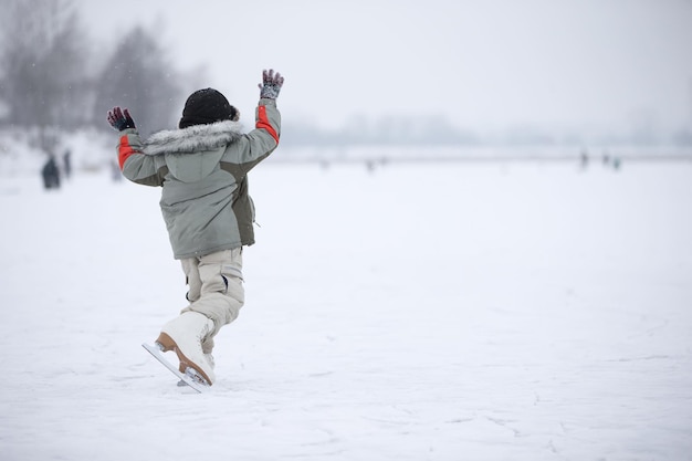 Um garotinho em patins enormes está andando no lago