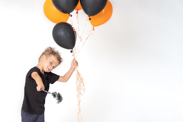 Um garotinho em uma camiseta preta segurando uma varinha mágica e balões laranja e pretos evoca em um fundo branco