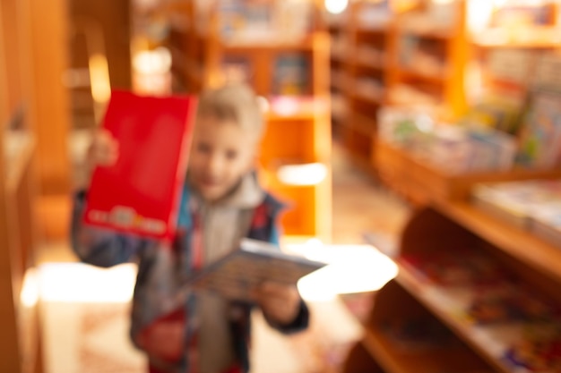Foto um garotinho escolhe livros em uma livraria fundo desfocado sem foco