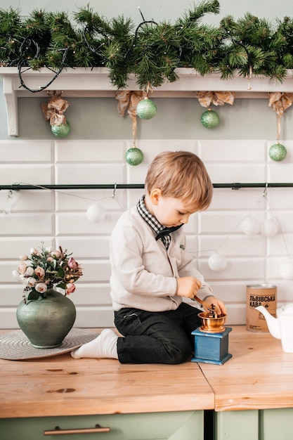 Um garotinho está sentado na mesa e se preparando para fazer biscoitos de Natal