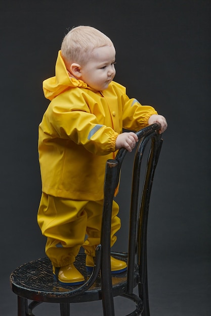 Um garotinho fica na cadeira em traje de bombeiro amarelo