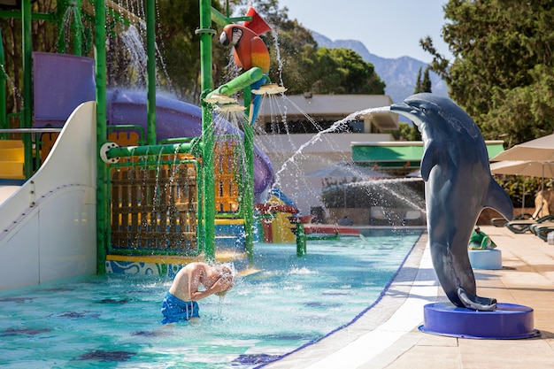 Um garotinho fofo se diverte na piscina do parque aquático Concept, férias de verão, descanso, diversão