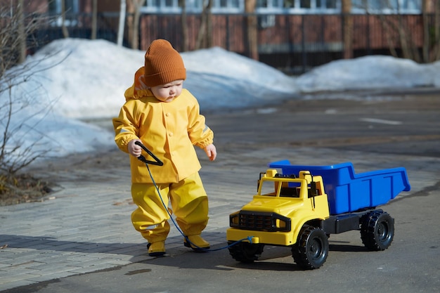 Um garotinho monta um grande caminhão de brinquedo por uma corda