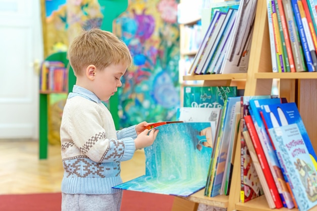 Um garotinho na biblioteca está folheando um livro infantil