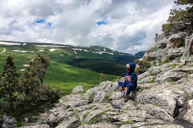 Um garotinho no fundo dos prados alpinos do planalto LagoNaki na Adygea Rússia 2021