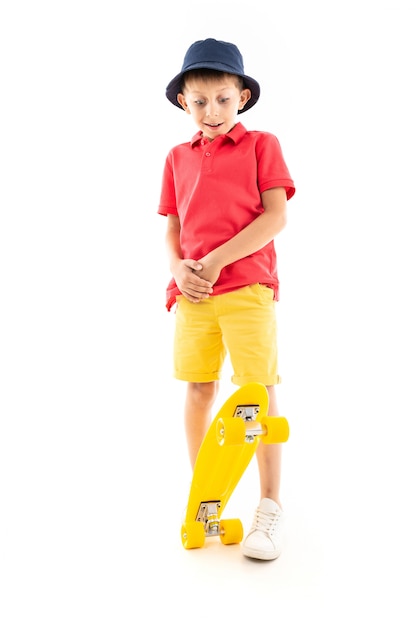 Um garotinho no Panamá, camisa amarela, shorts vermelho e tênis branco fica e segura um centavo amarelo